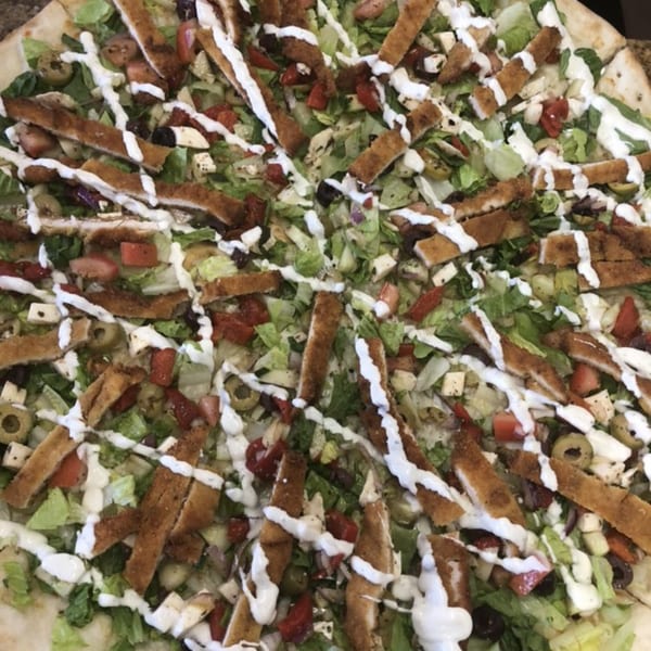 Fabio's Pizzeria's salad pizza, topped with crispy chicken, fresh greens, tomatoes, olives, and dressing.